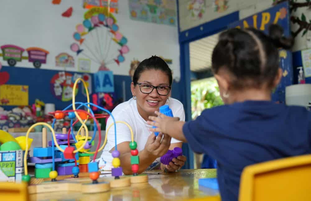 Nancy smiles as she plays blocks with a student in her classroom.