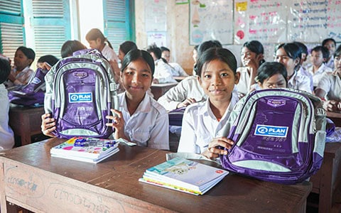 Girls holding up purple backpacks available through the Paramount and Plan International partnership